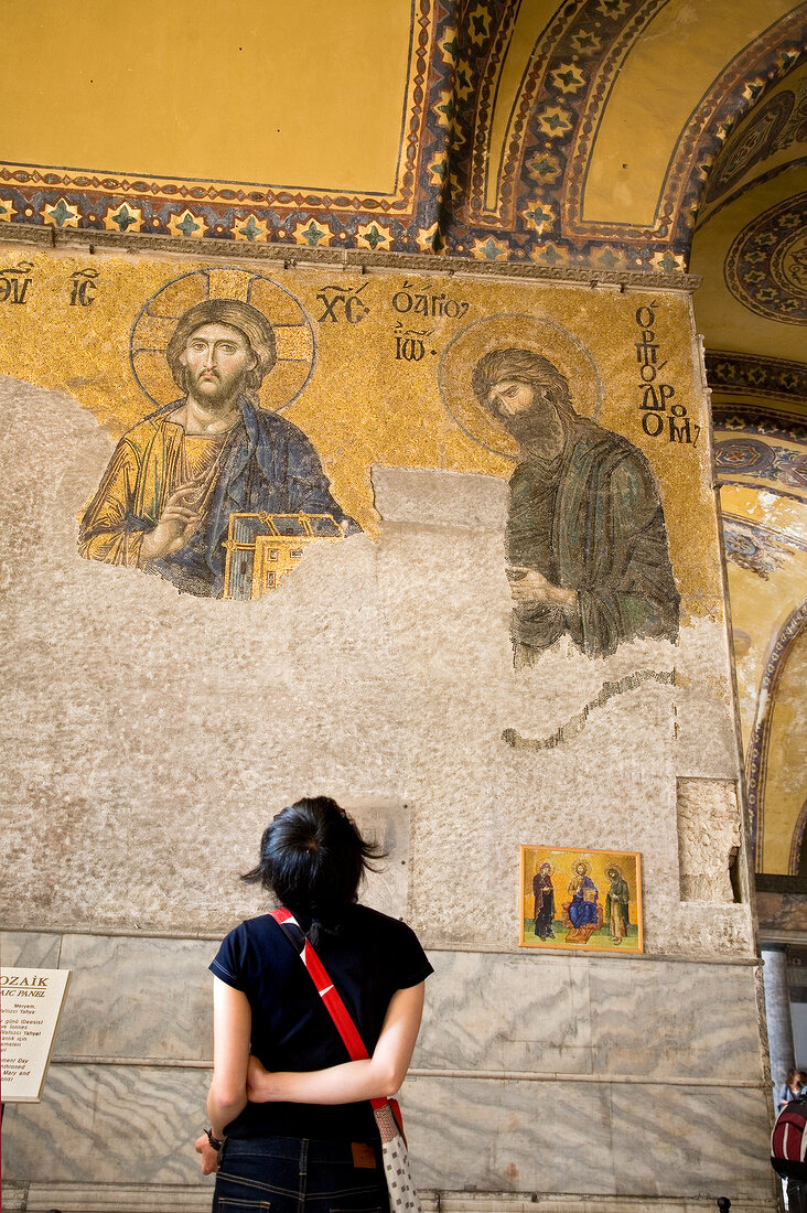 Rear view of woman looking at mosaic of Jesus on wall in Hagia Sophia, Istanbul, Turkey