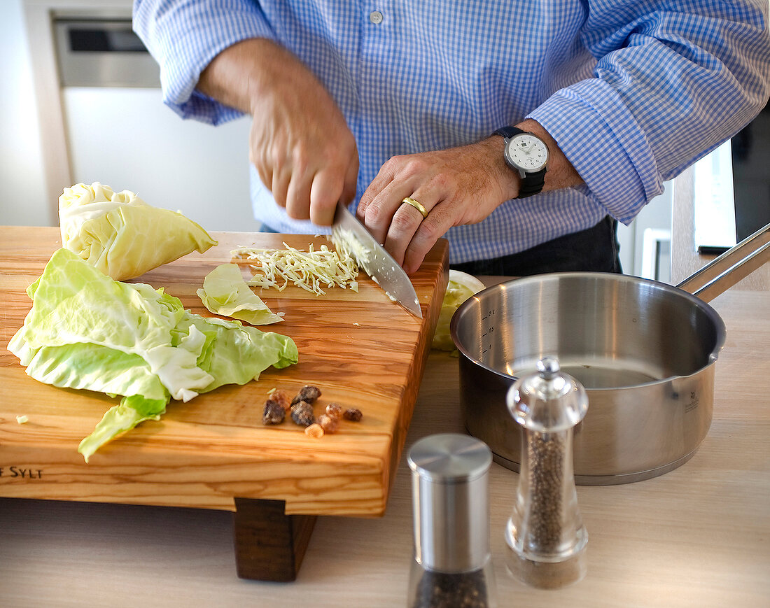 Lettuce leaves being chopped with knife on cutting board