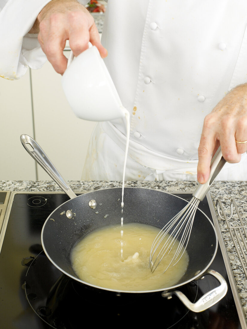 Close-up of man's hands whisking while pouring ingredient in pan