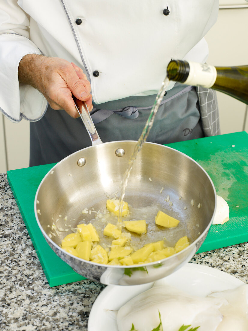 Man's hand pouring liquid from bottle in pan