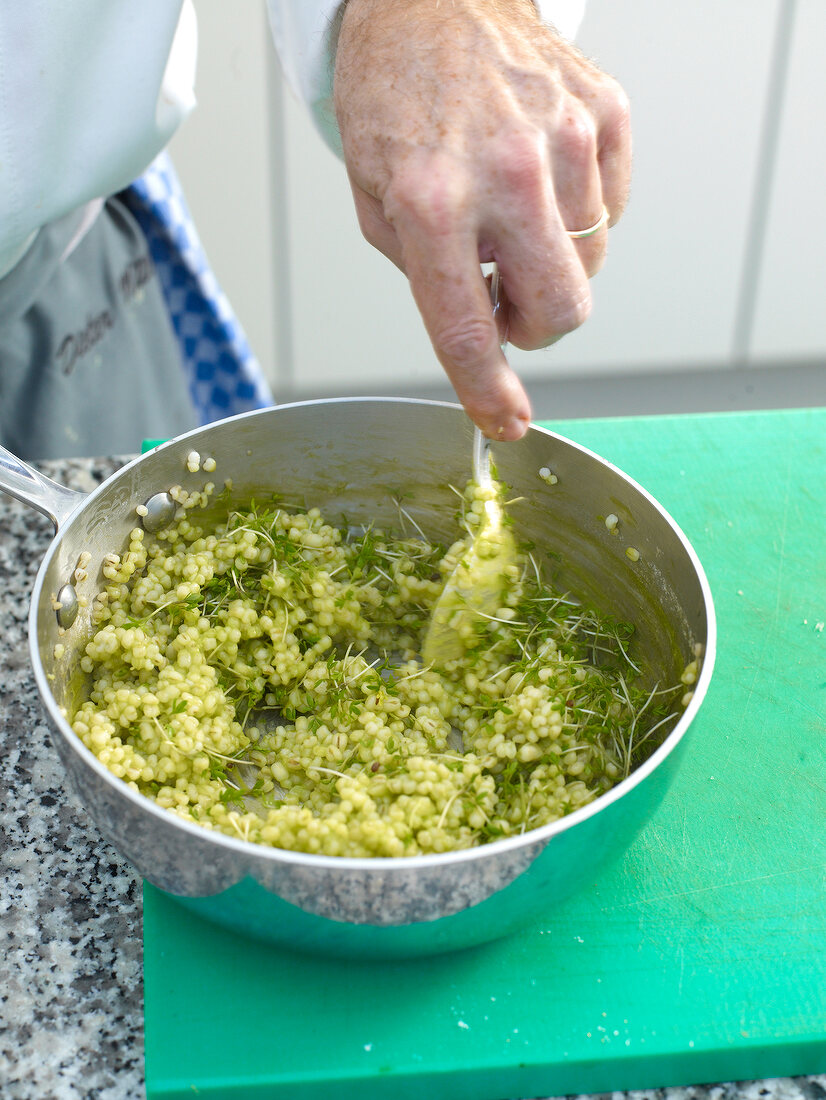 Cress and barley being mixed in pan
