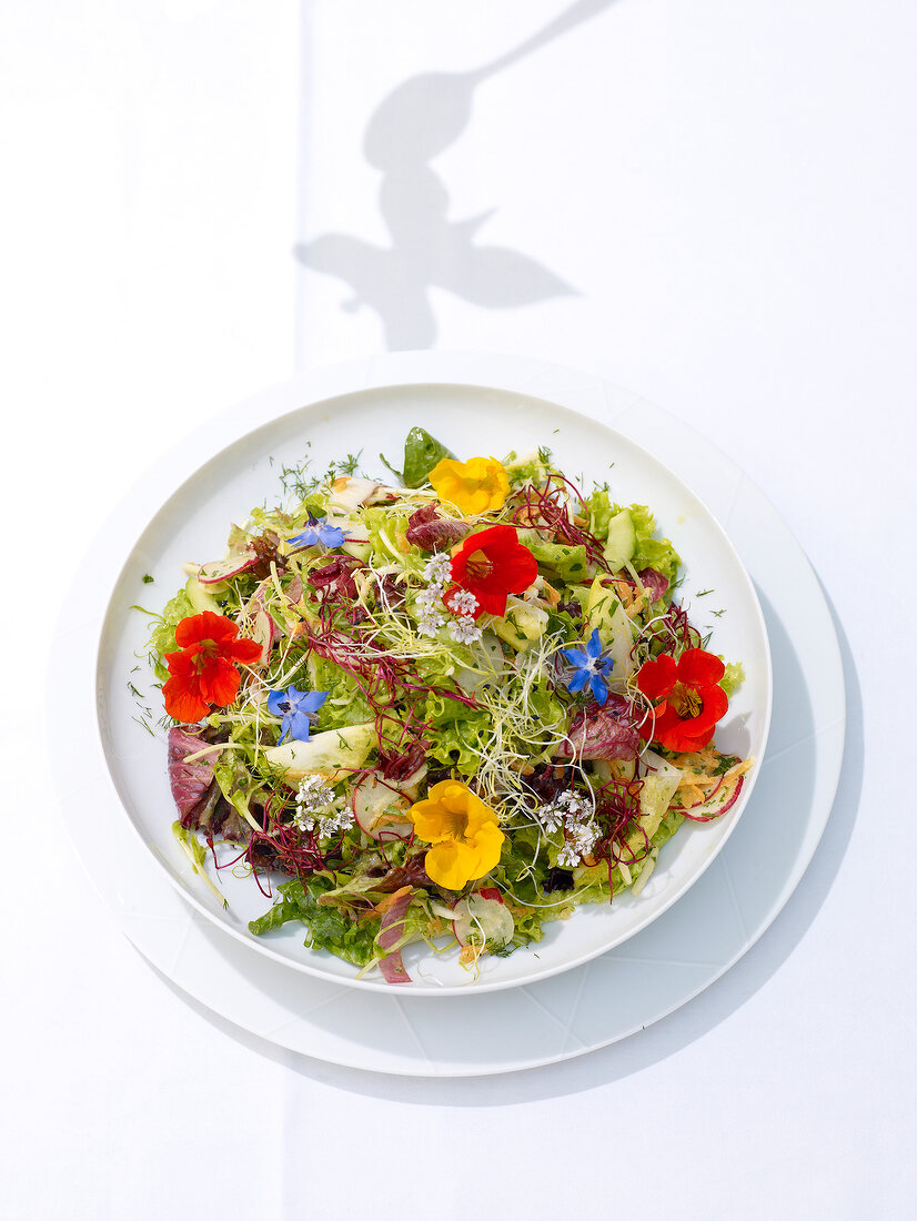 Vegetable salad garnished with flowers on plate