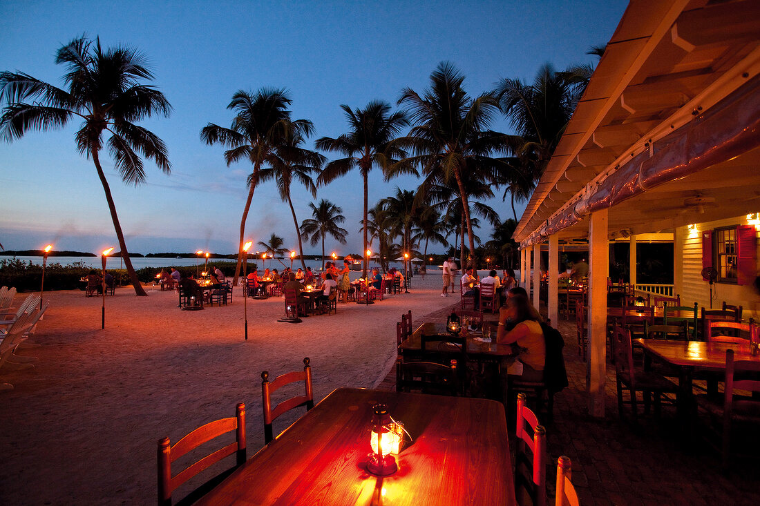 Guests sitting at tables in Morada Bay Beach Cafe at evening, Islamorada, Florida, USA