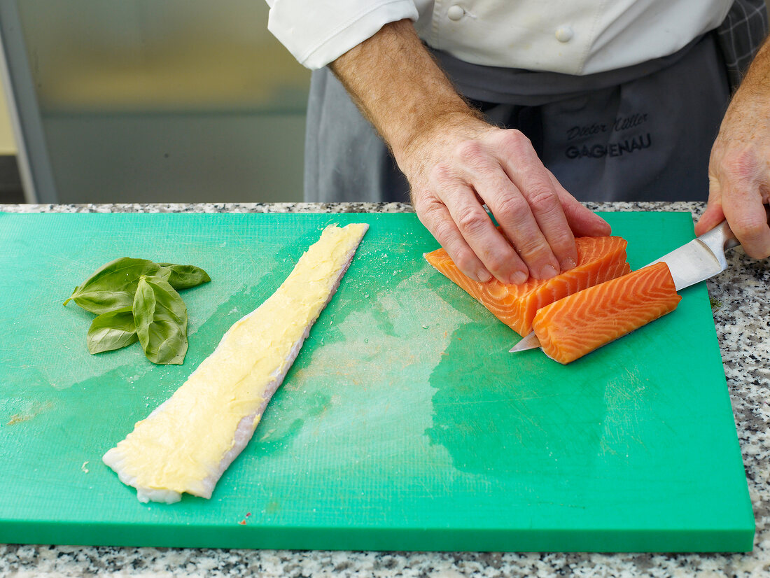 Close-up of man's hands chopping meat with knife on cutting board