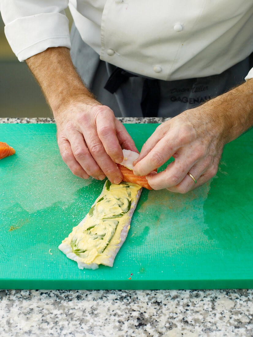 Close-up of man's hands rolling sole roulade on cutting board