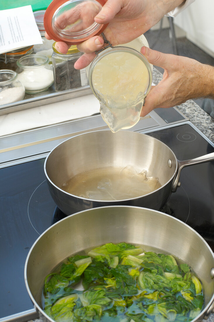 Adding ingredients to sauce pan while preparing lettuce sauce