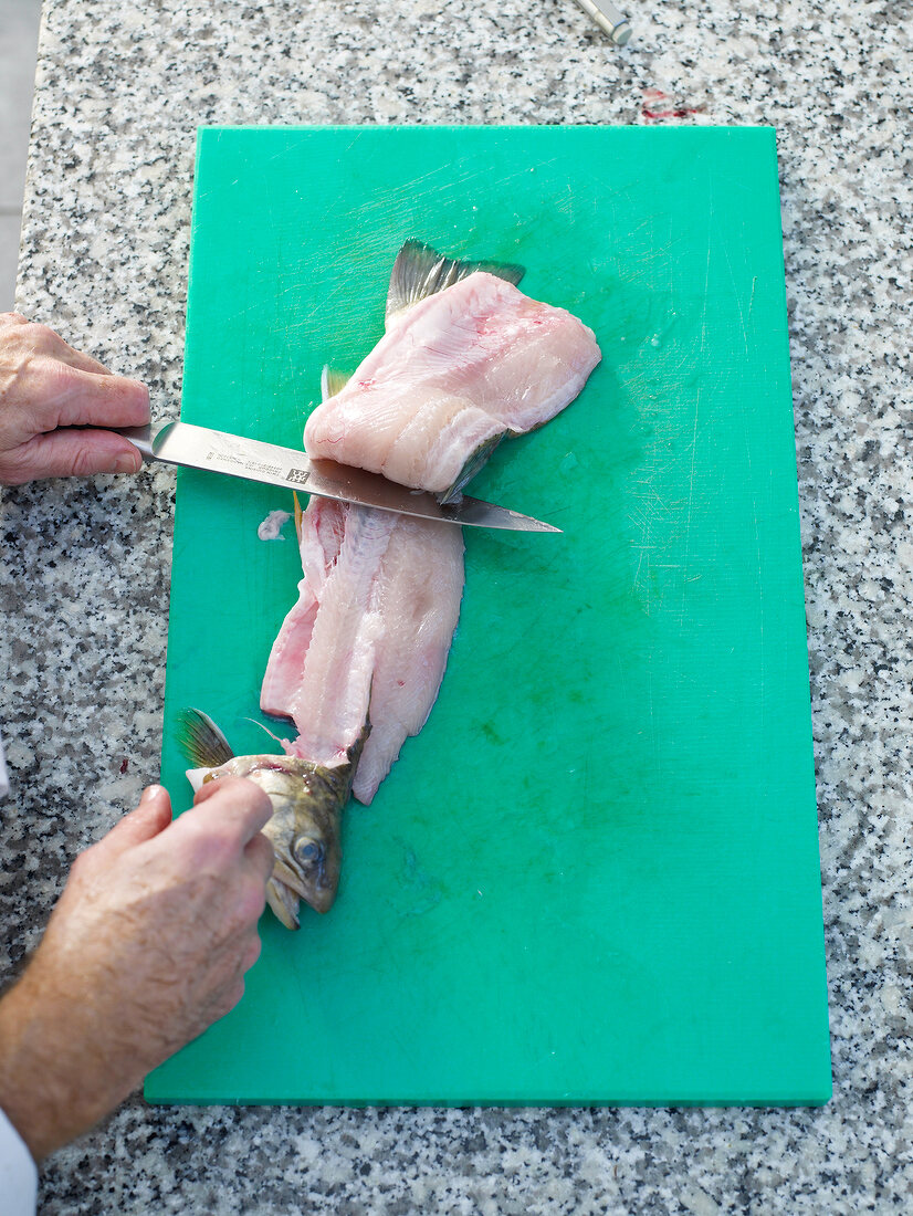 Arctic char being sliced on green chopping board with knife