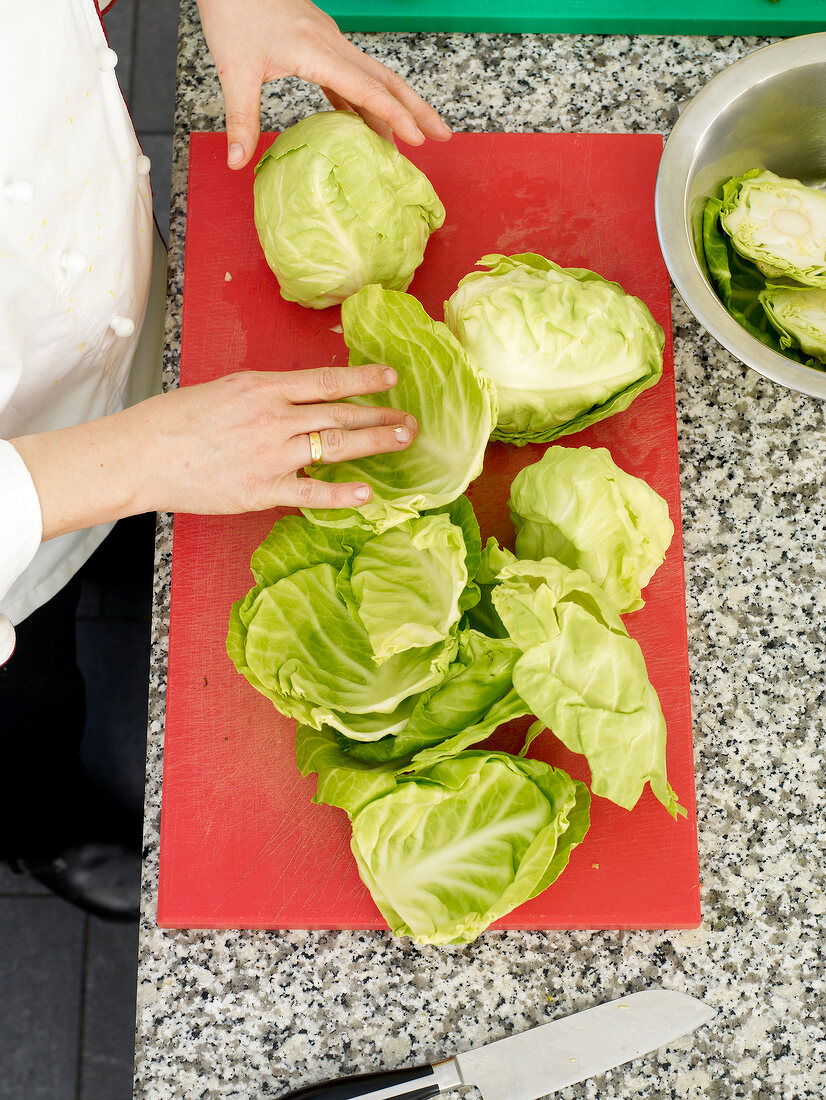 Chef cleaning and slicing cabbage on board for preparing cabbage balls