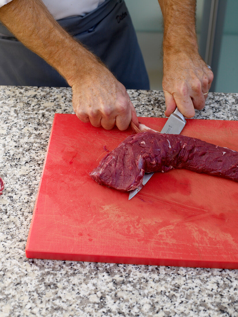 Venison being sliced on cutting board