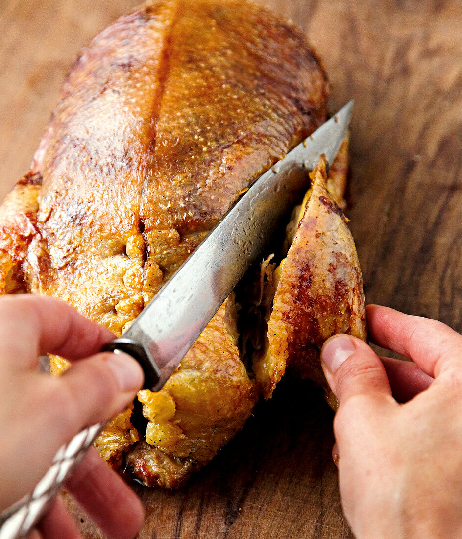 Close-up of roasted duck's leg being cut