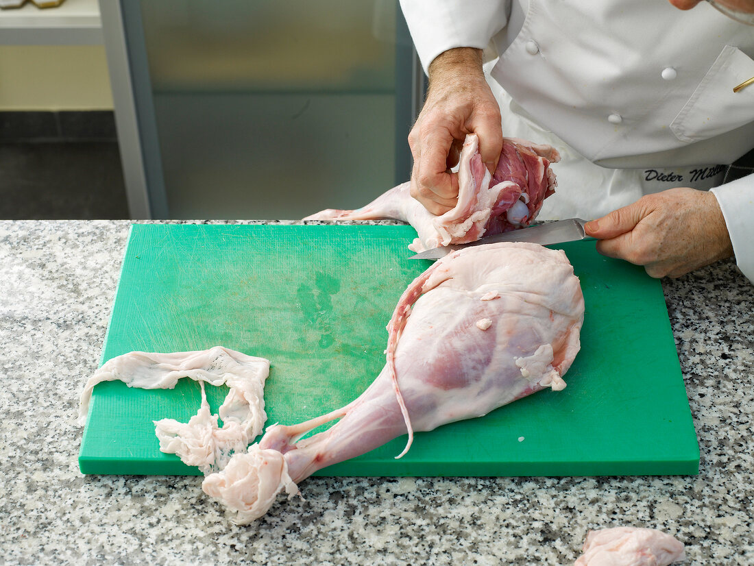 Chef cutting lamb's leg with knife