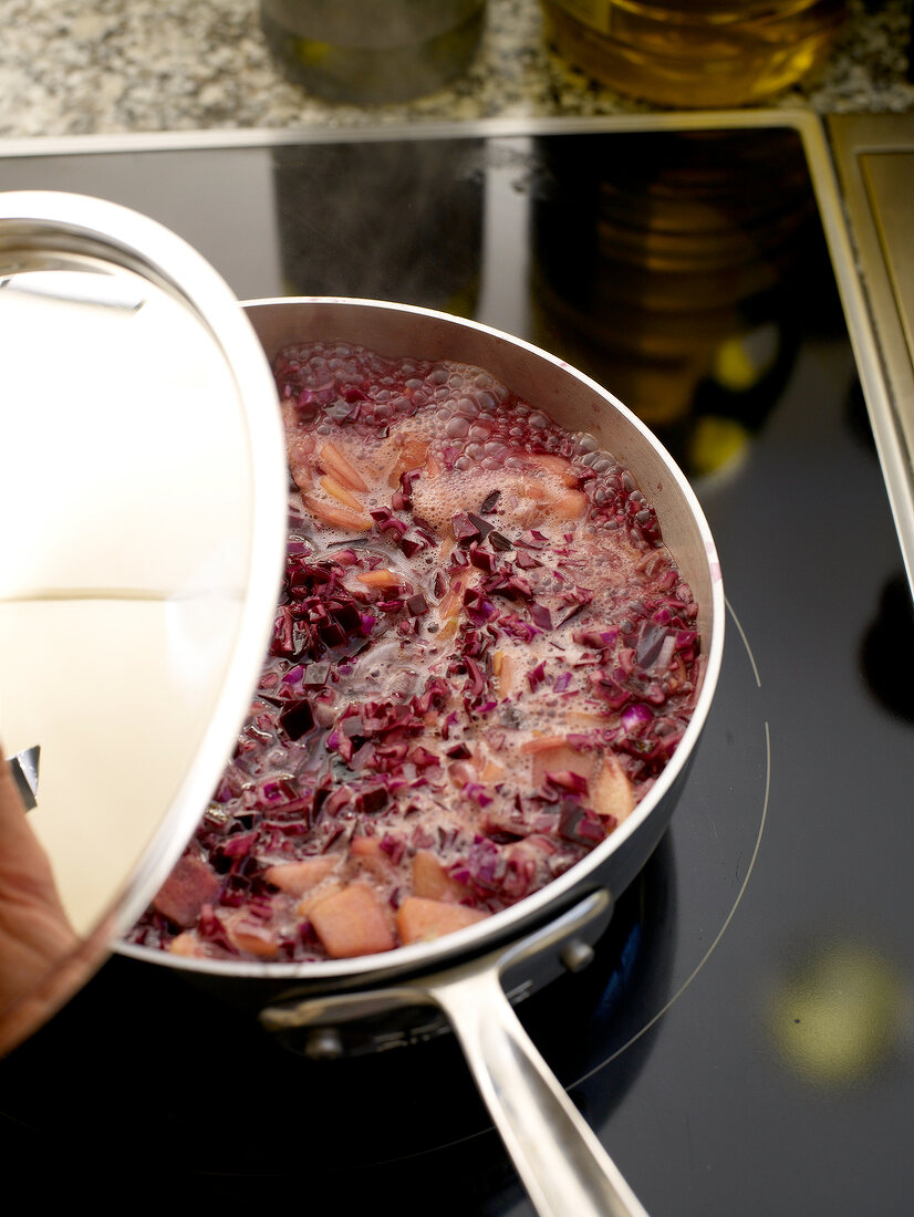 Cooking red cabbage and apple pieces in saucepan