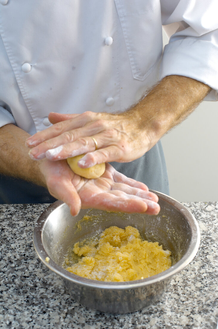 Making balls of batter of shredded potato and eggs for preparation of dumplings