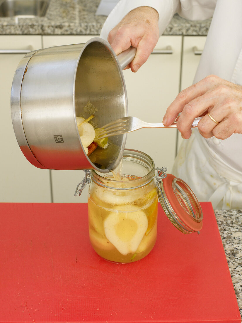 Putting boiled pears with spices in glass jar