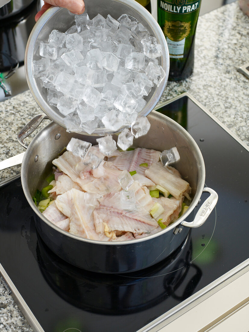 Adding ice in fish stock mixture in pot
