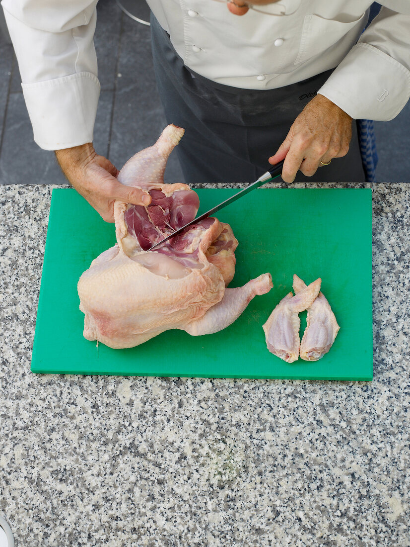 Cutting chicken on chopping board