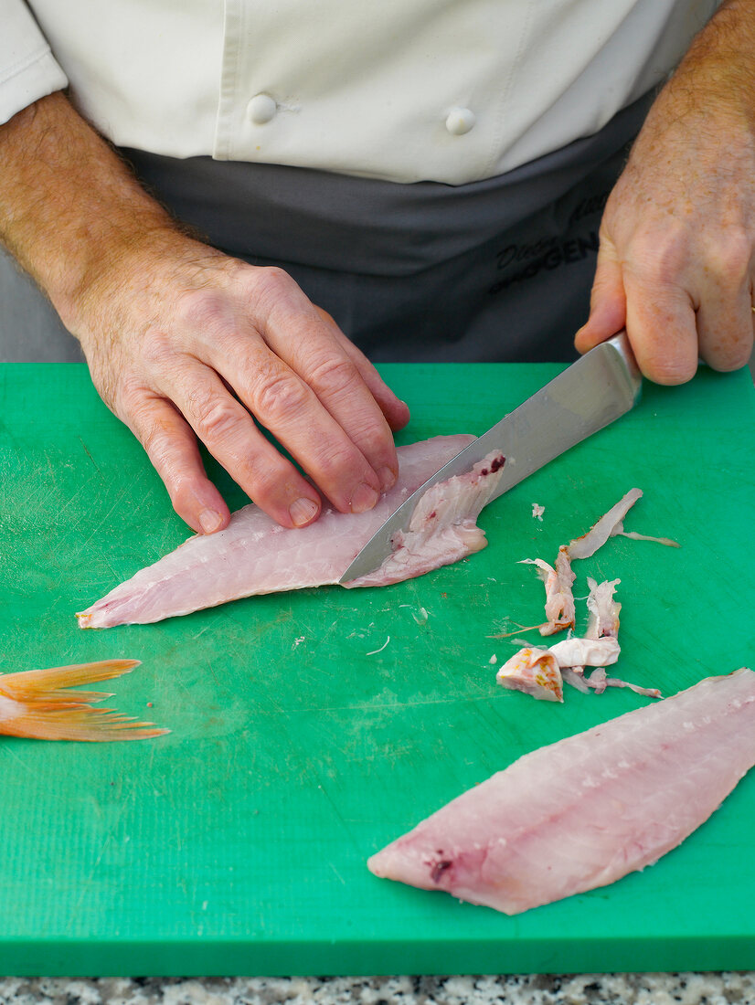 Filleting red mullet by knife on chopping board