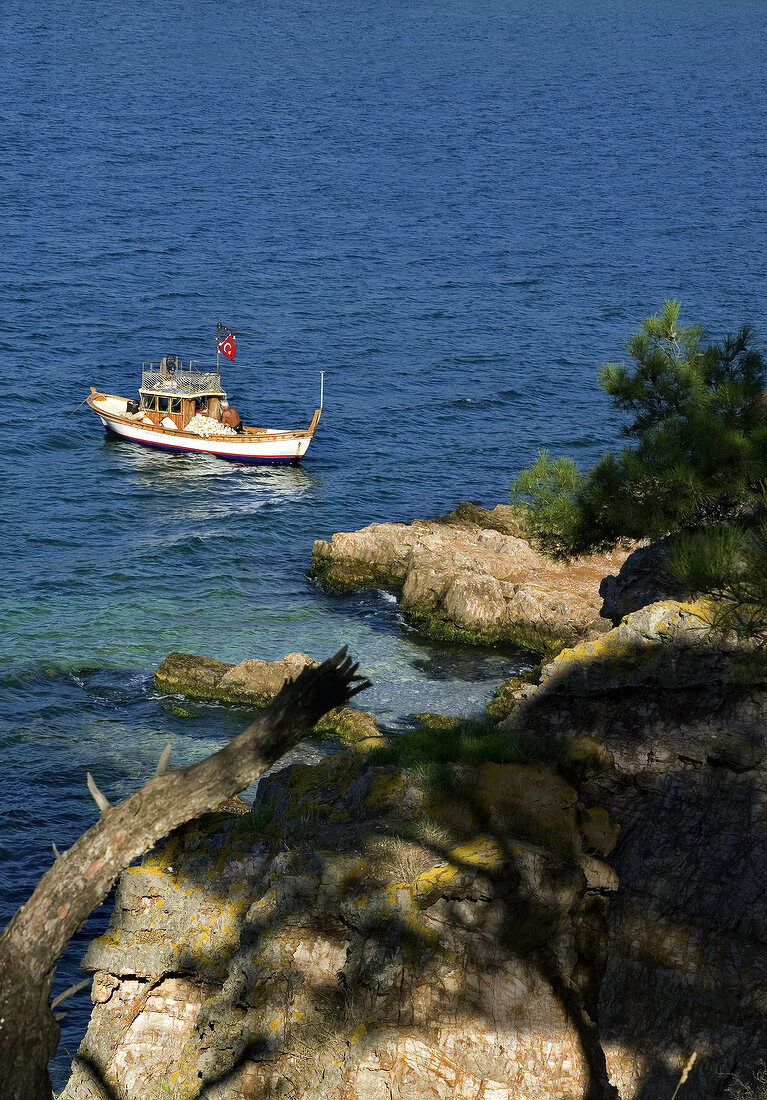 View of fishing boat in sea and rocky coast, Turkey