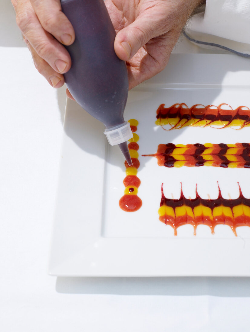 Plate being decorated with different type of fruit sauces