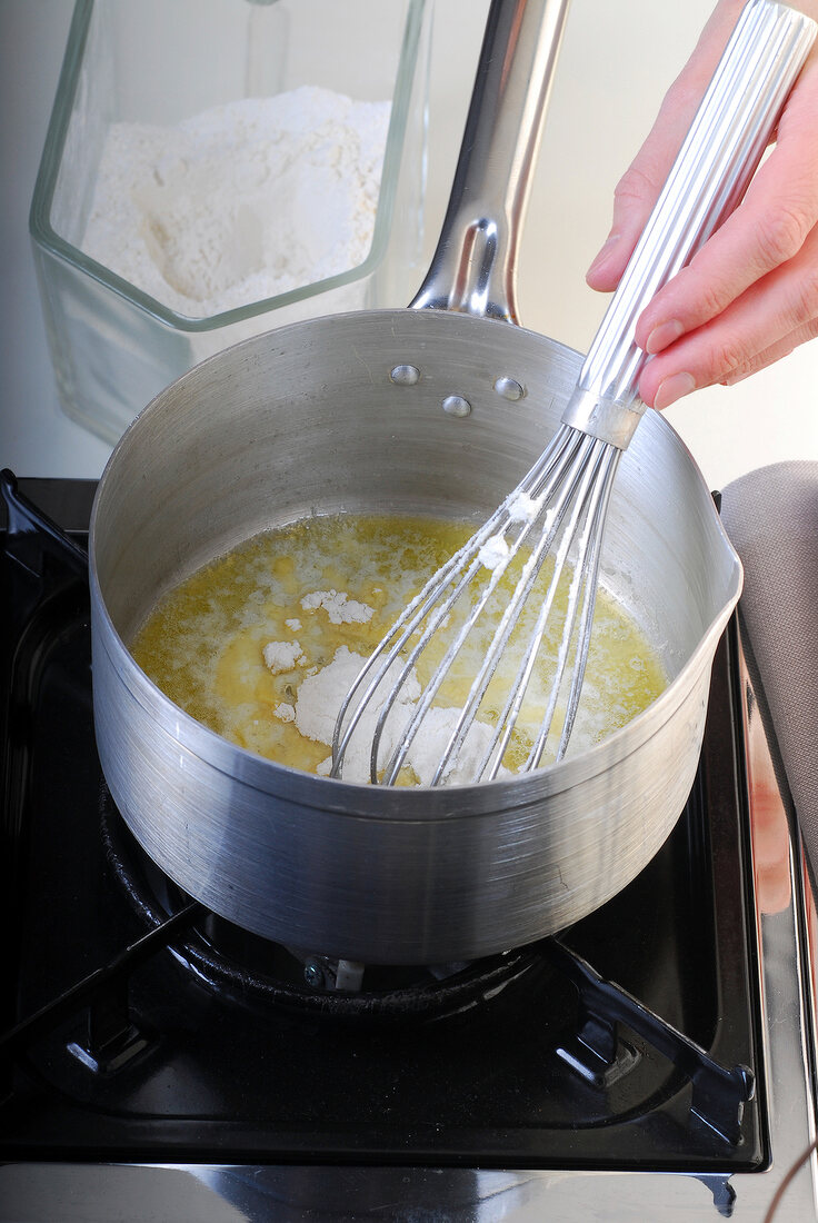 Flour being added in sauce pan for preparing bechamel sauce, step 1