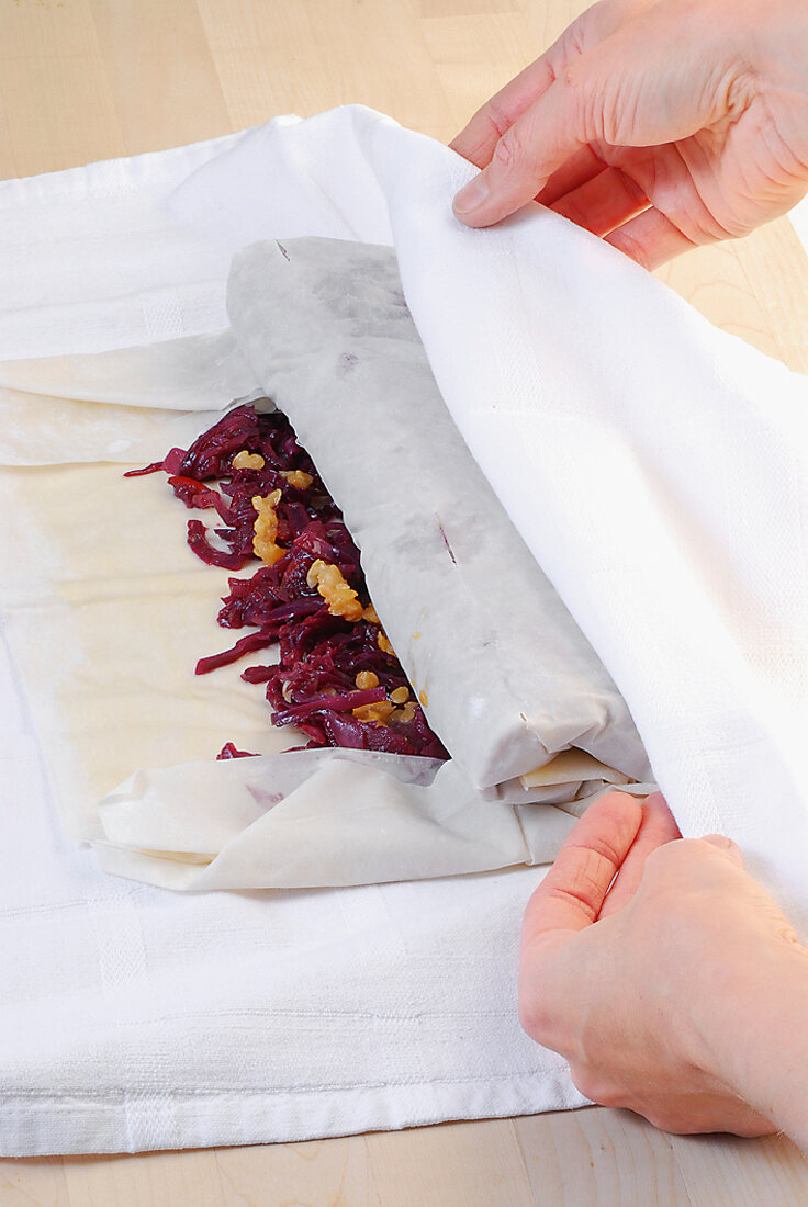 Baked red cabbage strudel with orange sauce on plate