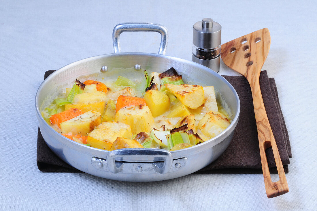 Winter vegetable gratin in steel casserole with spatula