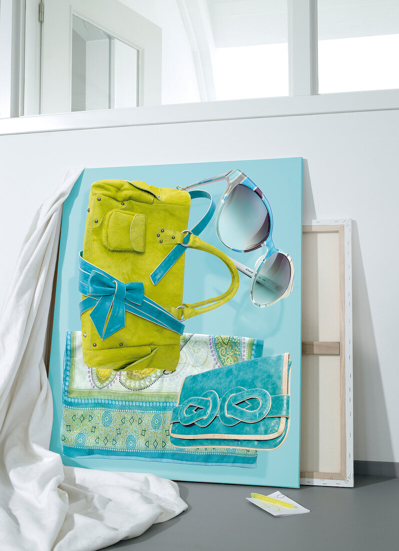 Close-up of bag, sunglasses, silk scarf and belt on turquoise colour