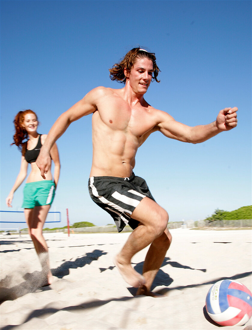 junge Leute am Strand, haben Spaß, spielen Fußball