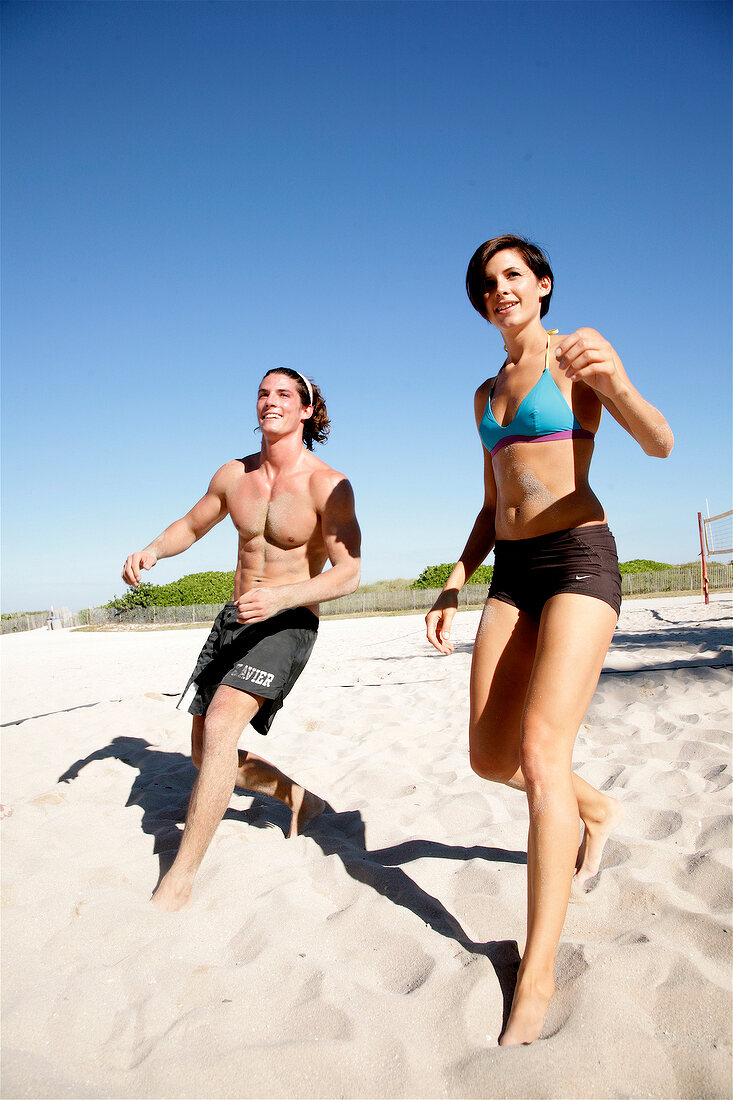 Young people playing football on beach