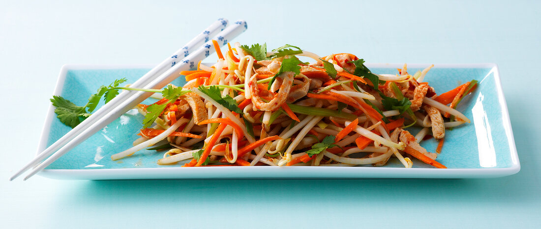 Soya sprout salad with chicken and vegetable strips in serving dish with chopsticks