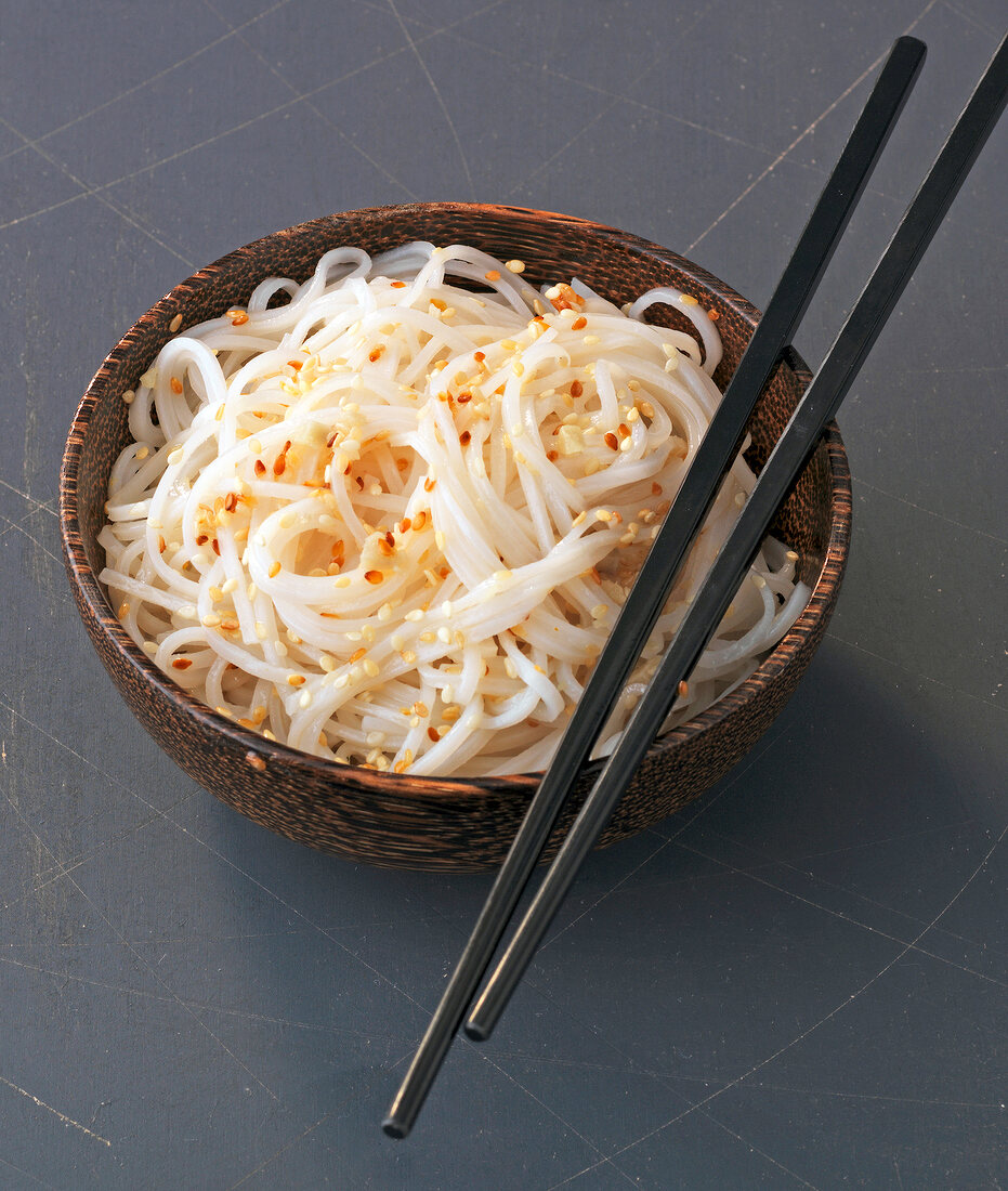 Ginger and sesame rice noodles in bowl with chopsticks