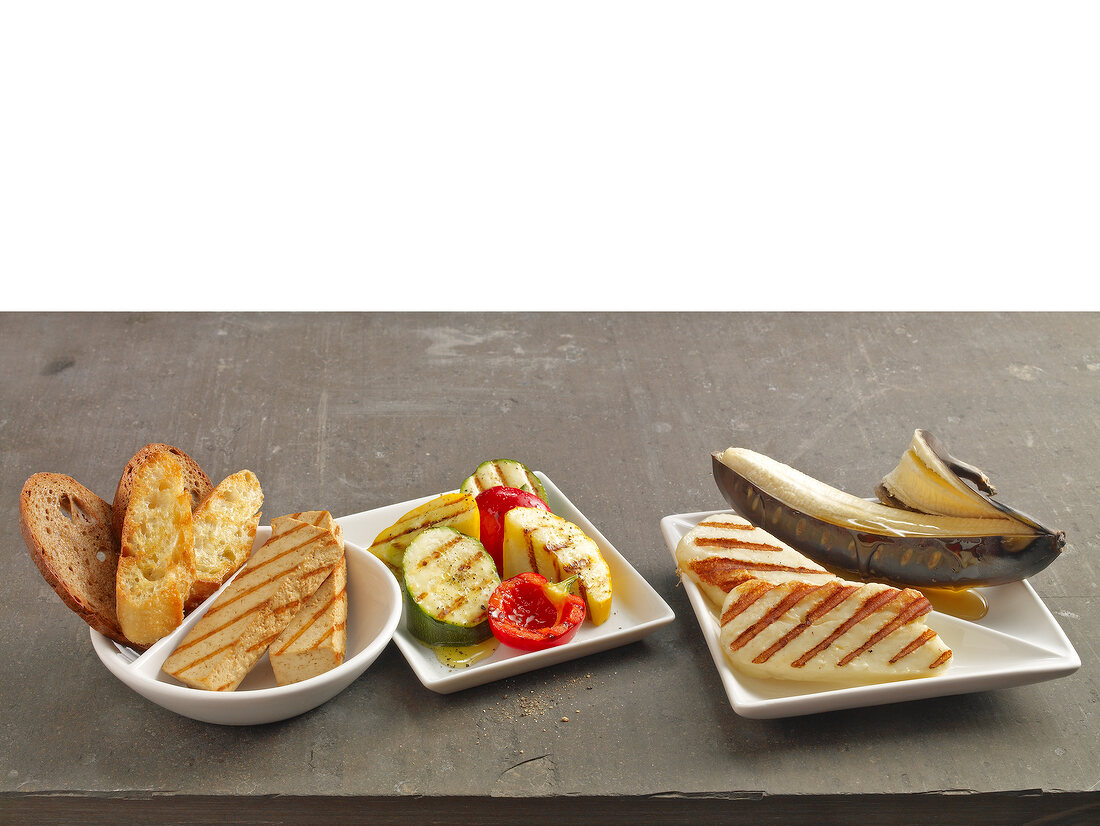 Grilled bread, grilled cheese and grilled vegetables with banana on plates