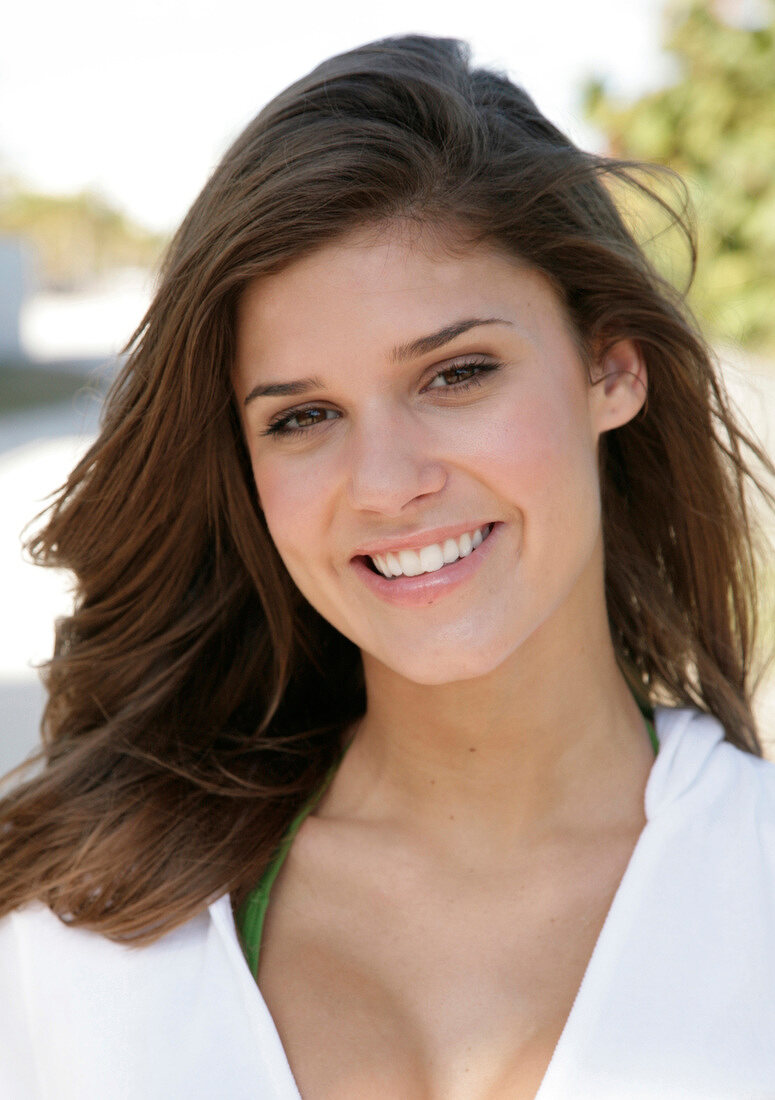 Portrait of beautiful dark haired woman wearing white zipper jacket smiling, close-up