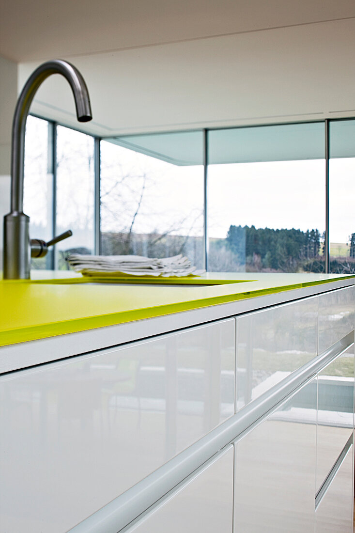Detail Kücheninsel mit gelbgrüner Arbeitsplatte und Küchenspüle