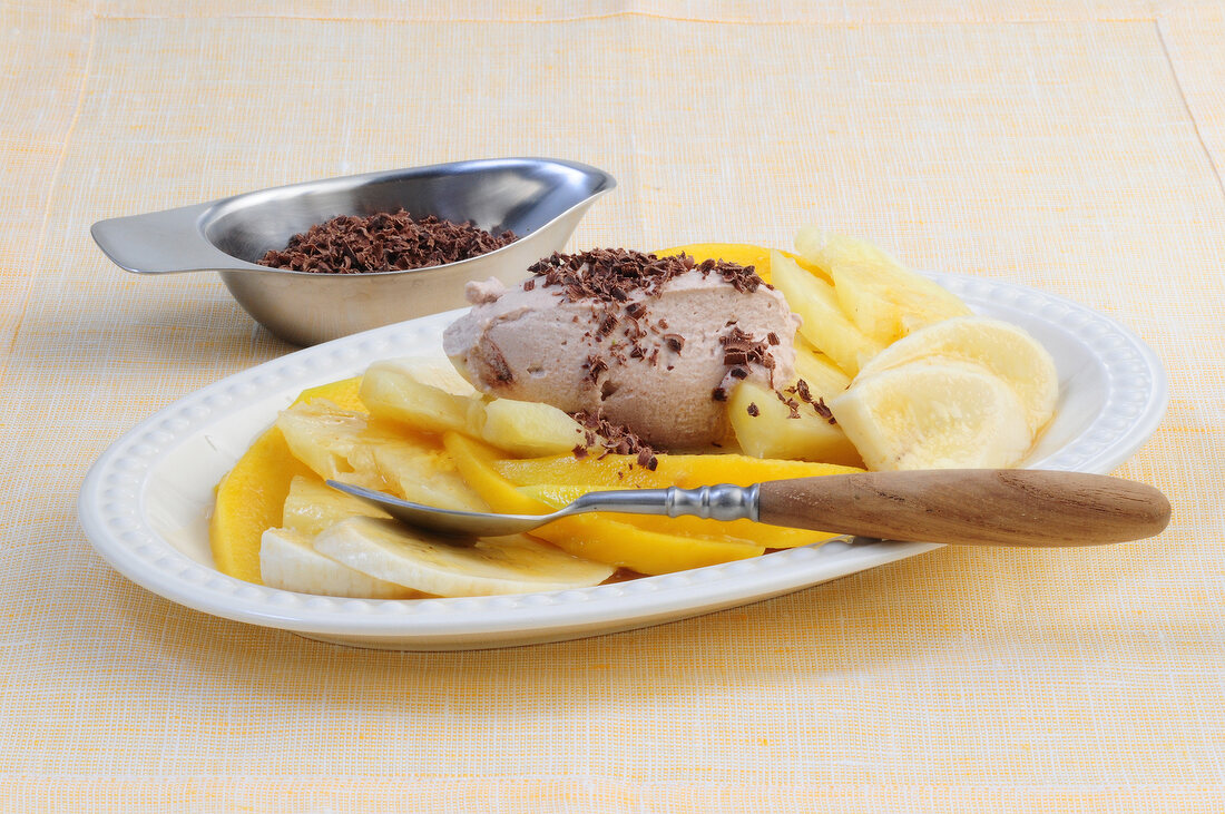 Pineapple and mango salad with ginger chocolate cream on plate