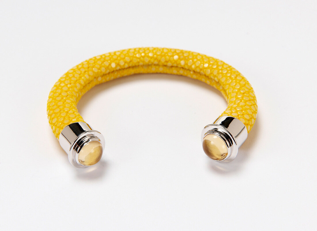 Close-up of yellow bangle made of stingray skin on white background