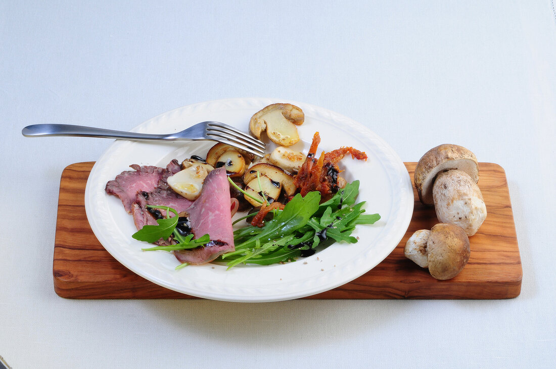 Porcini mushroom salad with roasted beef on plate
