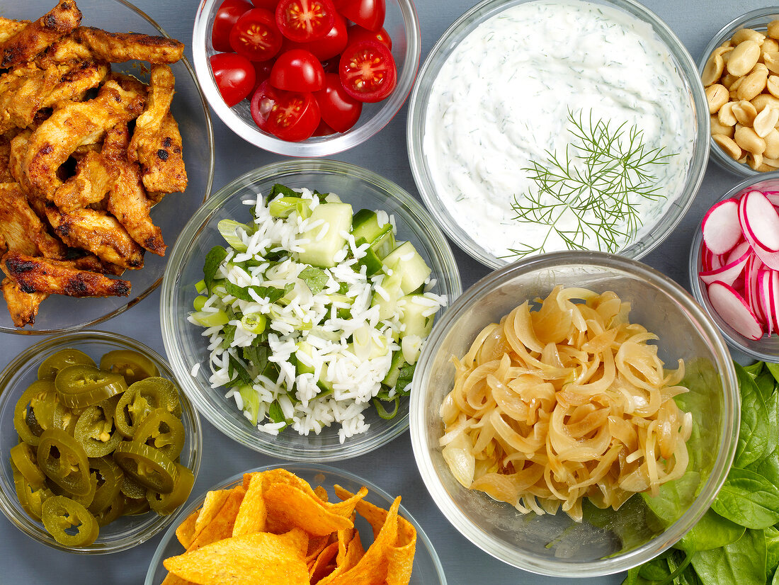 Close-up of various ingredients for wraps in bowls, overhead view