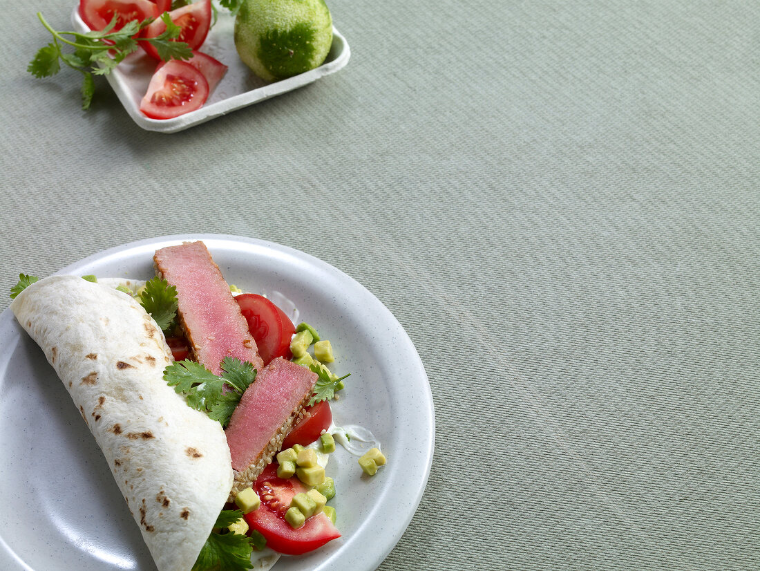 Close-up of wraps with tuna, avocado and tomato on plate