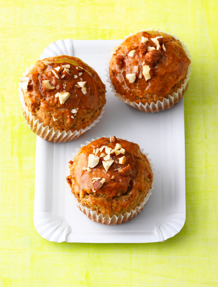Three banana muffins with almonds topping on paper plate