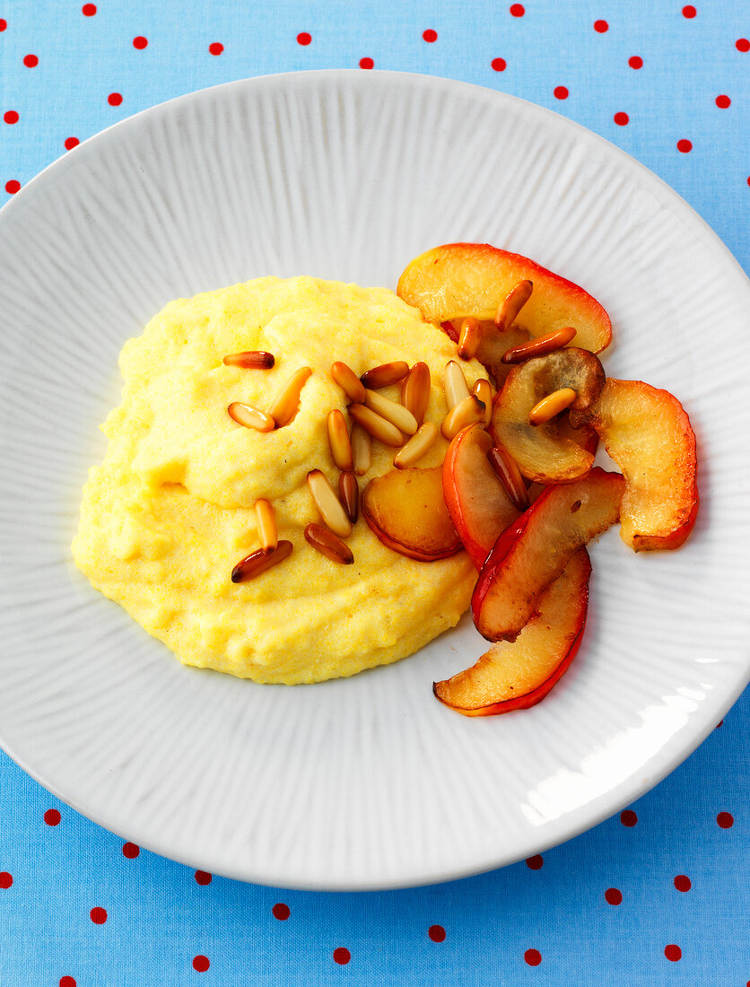 Fried apple slices with honey and polenta on plate