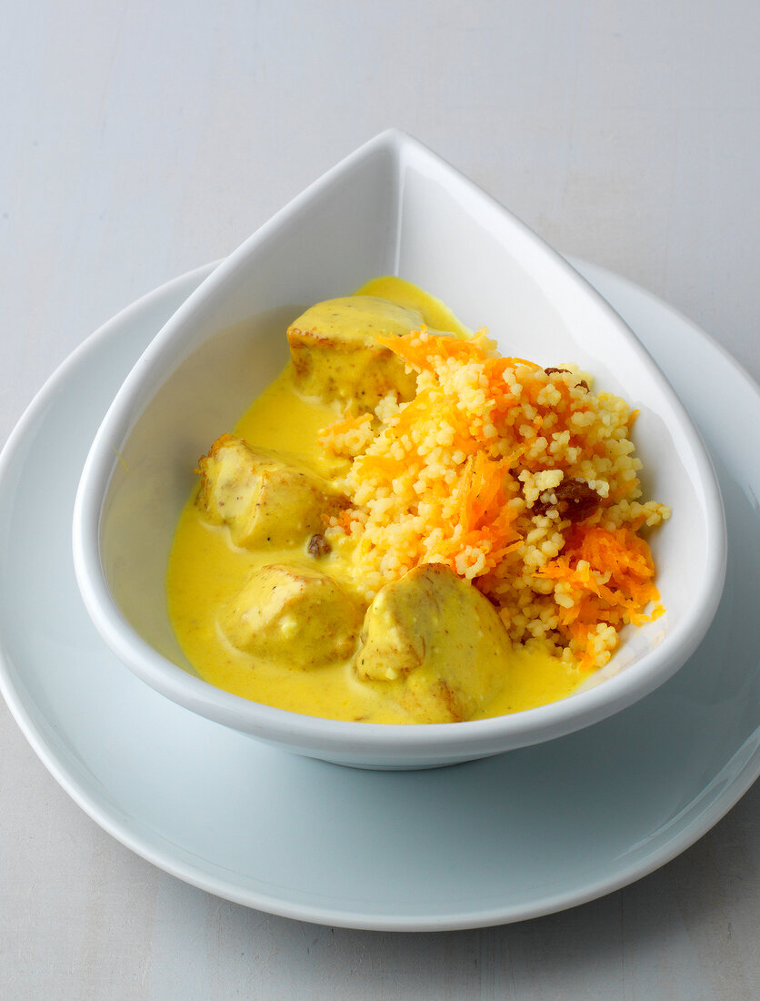 Cream curry with carrot couscous in bowl