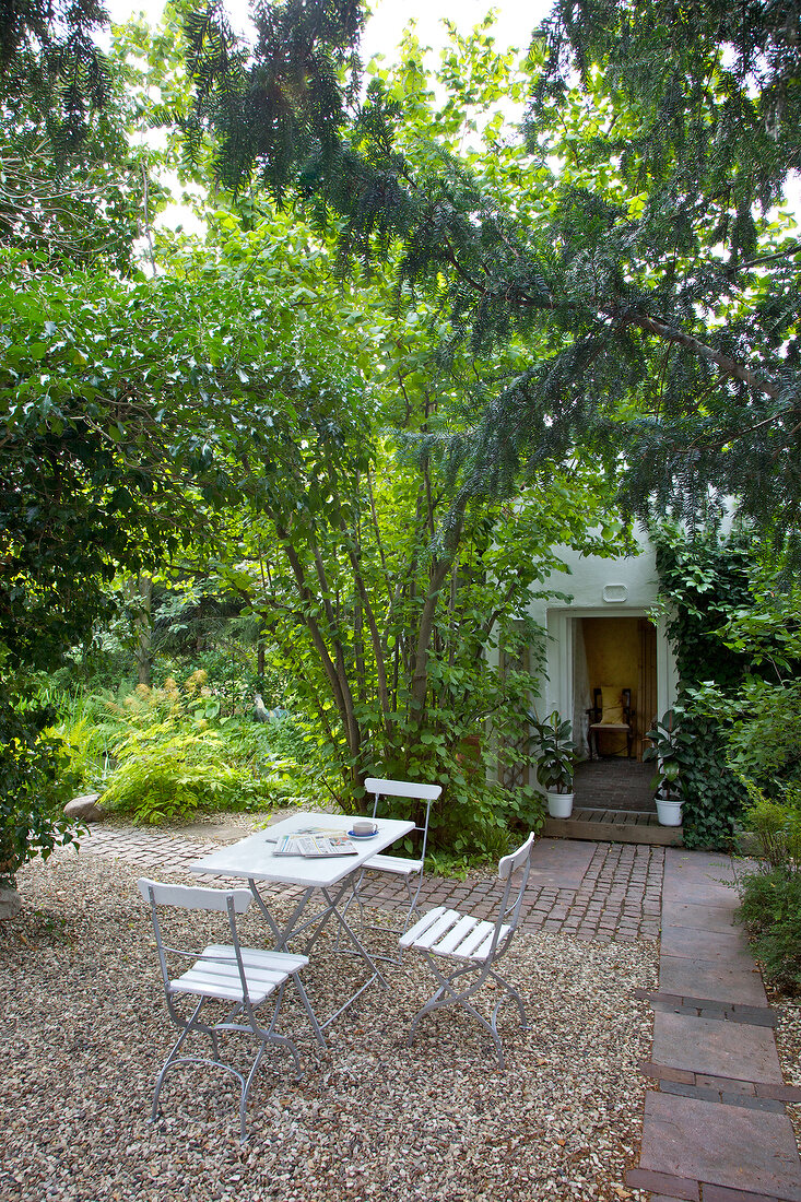 Seating in shade with pebbles and garden shed in garden