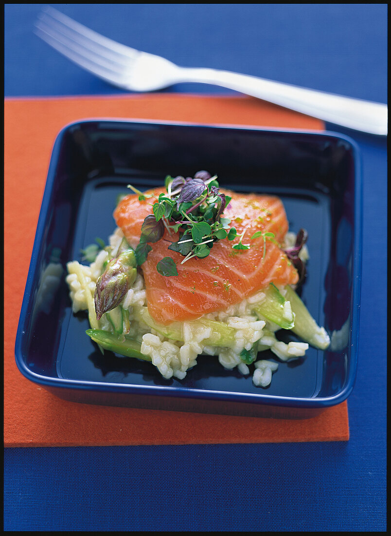 Raw marinated salmon with risotto and asparagus on square plate