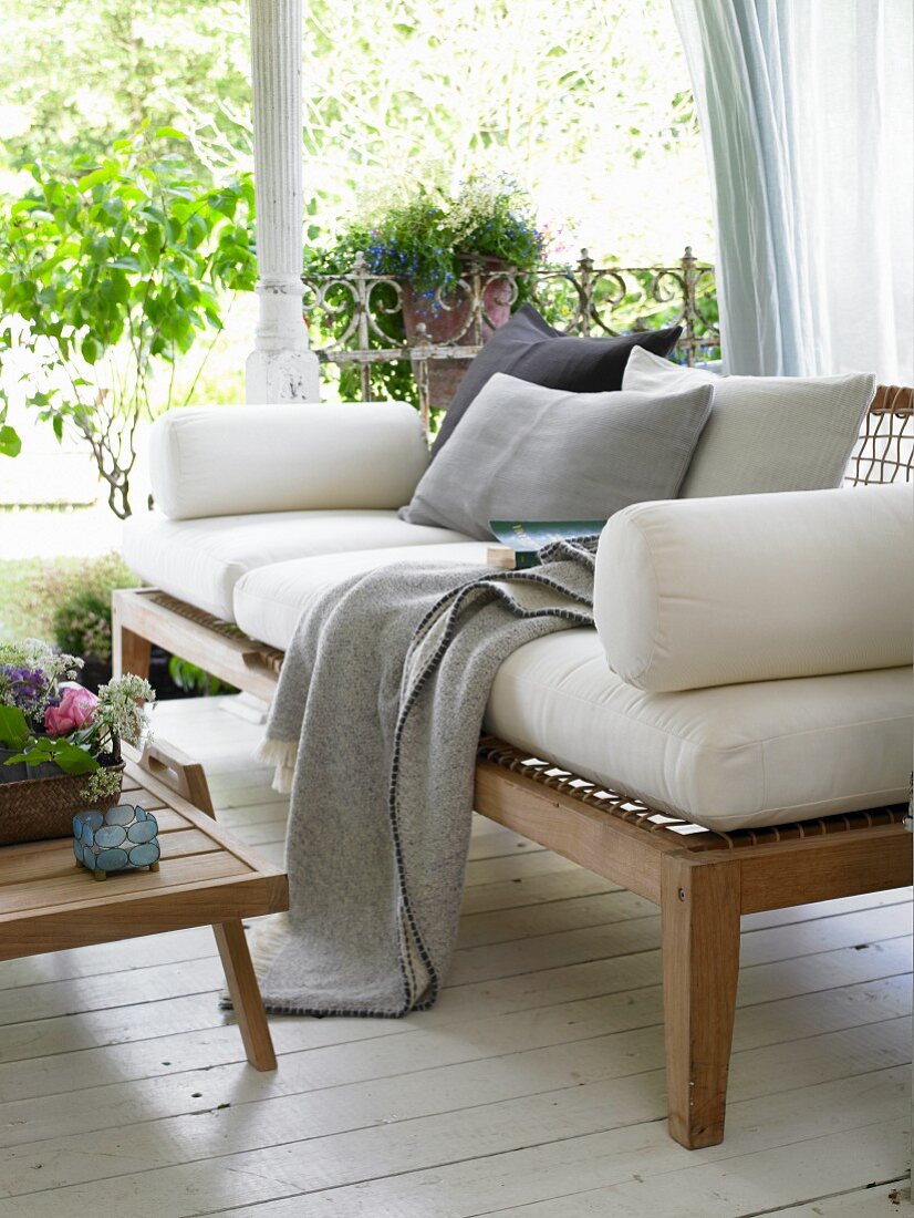 Sofa aus Holz mit Polsterauflagen auf sommerlicher Veranda