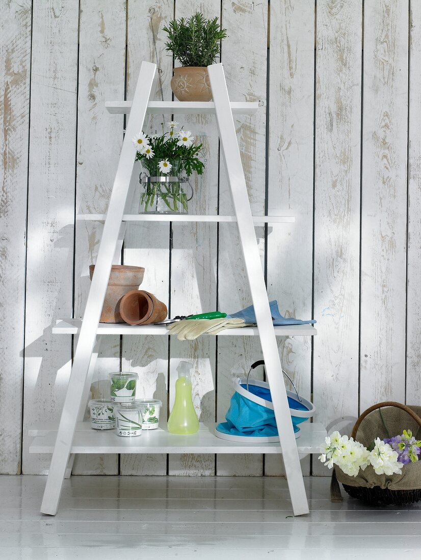 White ladder shelf in front of wooden wall