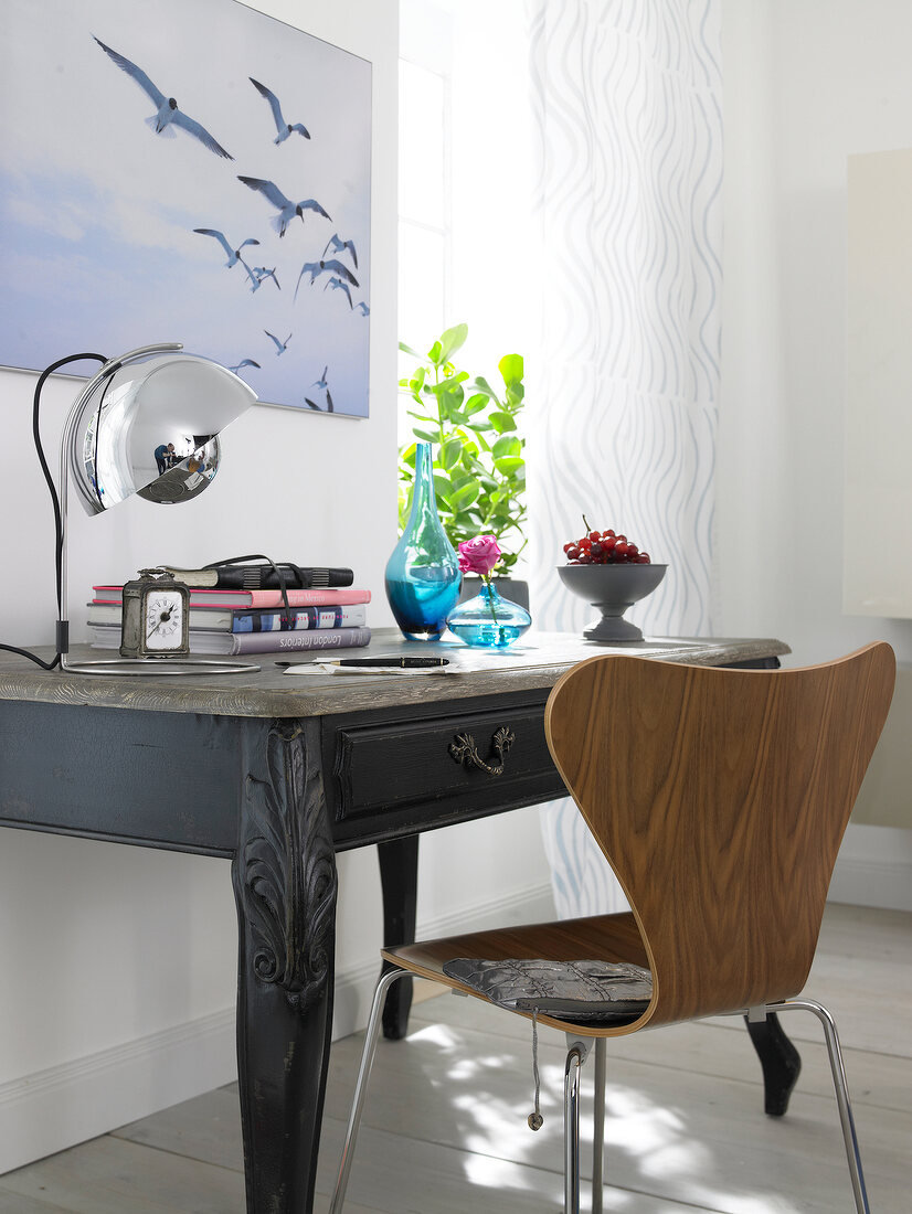 Antique styled desk and oval chair against wall with seagull wall painting