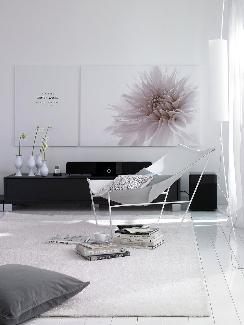 View of living room in white with large floral motif painting on wall and couch