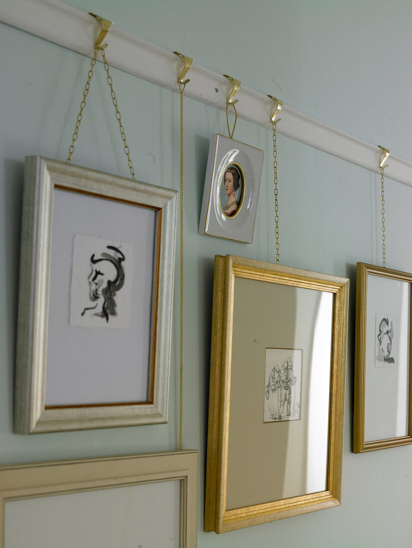 Several pictures frames with brass chain on wall