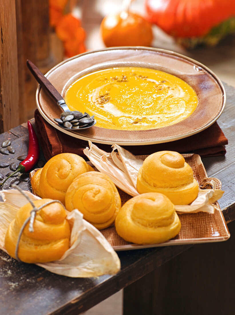 Pumpkin soup on plate and corn bread snails in serving dish